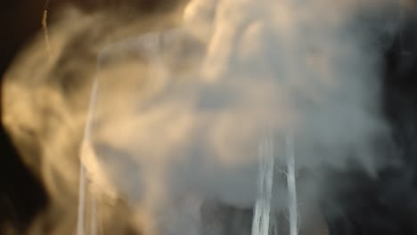 portrait of scary guy in thematic costume of halloween skeleton exhaling cigarette smoke from mouth