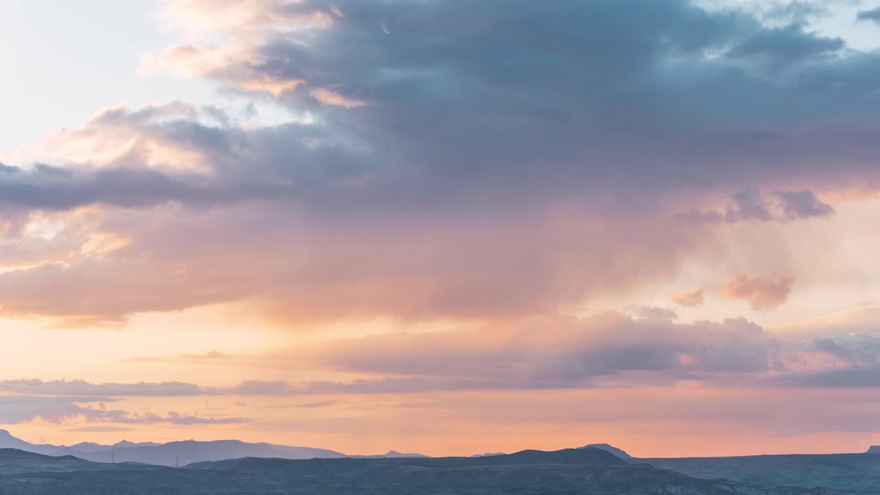 Colorful moving clouds during sunset over distant hills