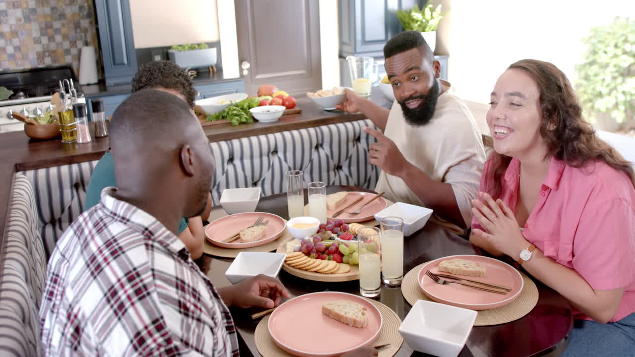 Groupe d'amis partageant un repas ensemble, riant et partageant de la nourriture à la maison.