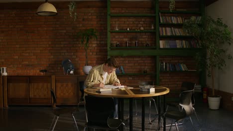 young man studying in a cozy library-style cafe