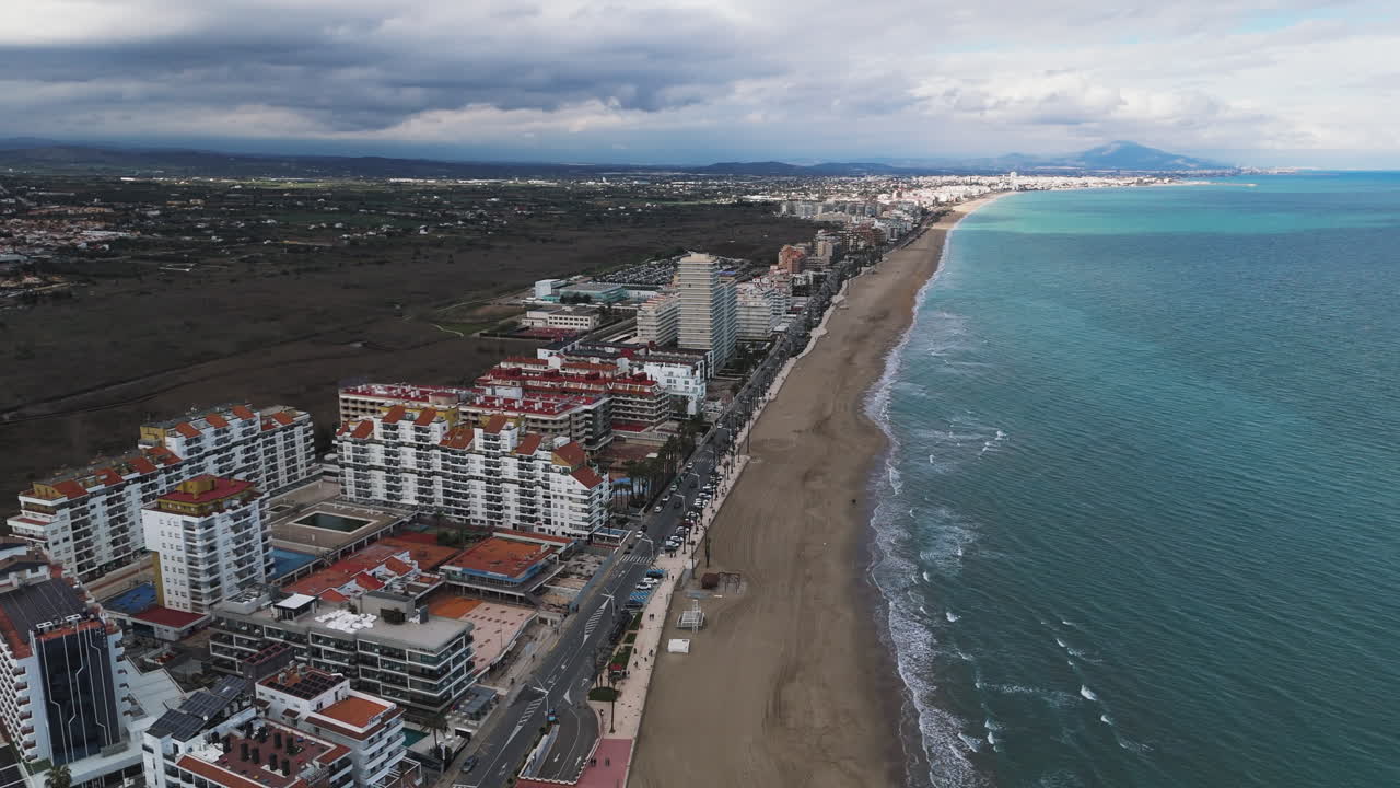 Straight aerial along Peniscola beachfront with tall resorts and turquoise waters