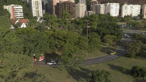 slow aerial descent with a highway through a green environment, panning up revealing residential buildings with a mountain behind in rio de janeiro at sunset