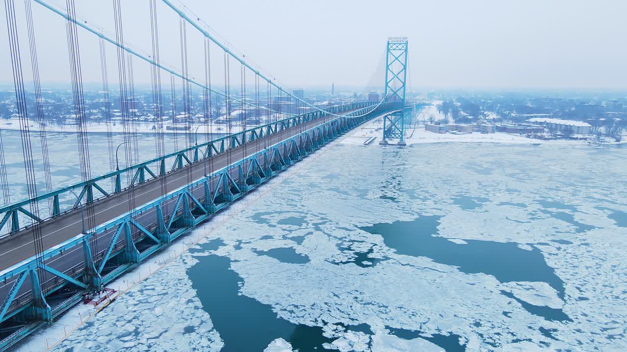 Ambassador Bridge stretches over icy Detroit River with heavy snow and frozen shoreline