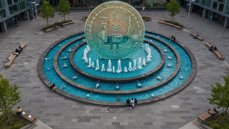 aerial view of a stunning fountain display featuring a large bitcoin symbol in a modern urban environment with visitors enjoying the scene