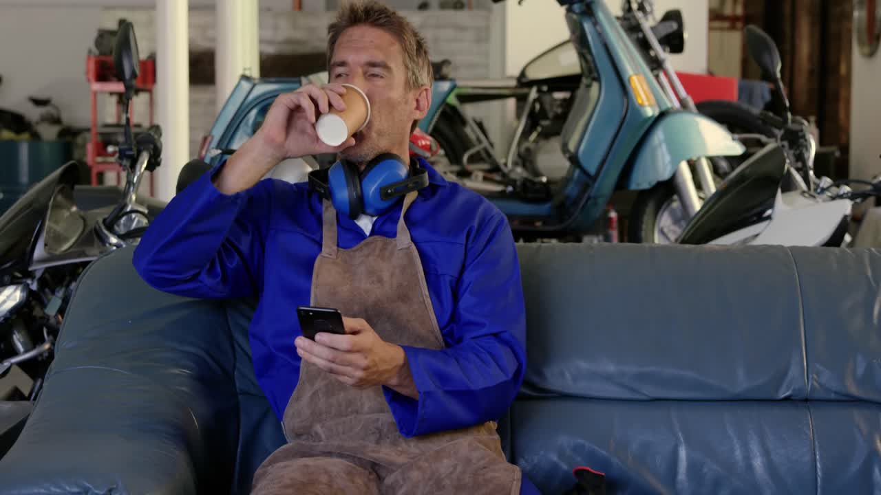 오토바이 수리 공장에서 휴대폰을 사용하는 남성 메카닉 4k