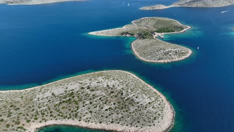 aerial high angle overview of small islands with rocky shores and blue waters in kornati national park, croatia, establishing pan up