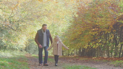 Vater-Spielt-Spiel-Und-Holt-Tochter-Auf-Einem-Familienspaziergang-Entlang-Der-Strecke-In-Der-Herbstlichen-Landschaft-Ab