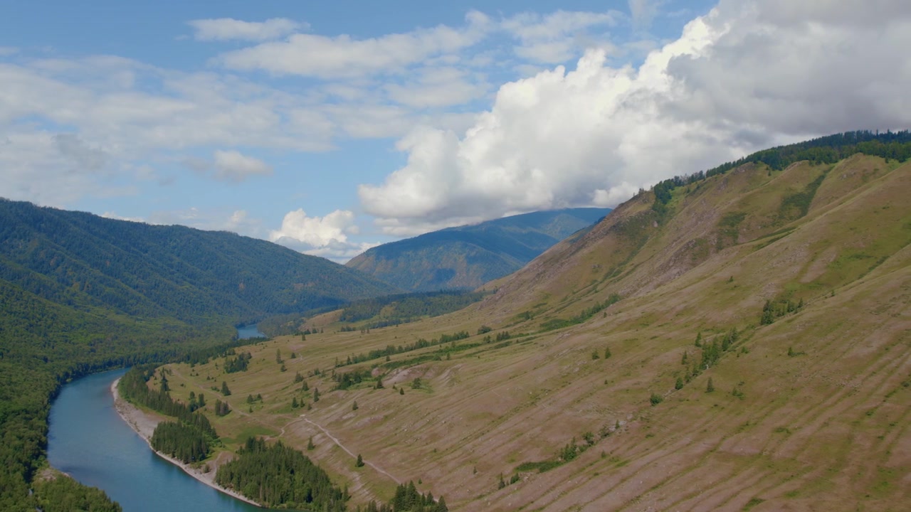 Riprese drone di dolci creste montuose verdi e macchie di foresta sotto un cielo nuvoloso drammatico nella Valle di Ak-Kem, Monti Altai, Russia, paesaggio selvaggio estivo.