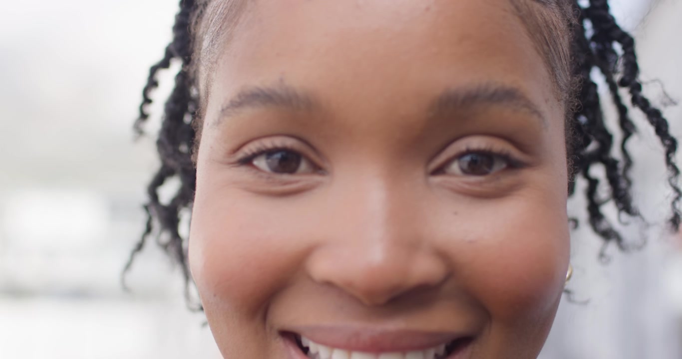 African American woman after cue, making eye contact, smiling with braids and earrings in close-up