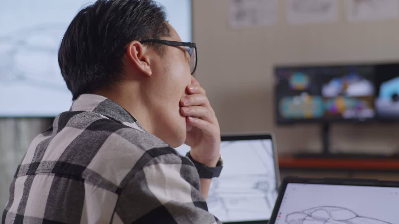 Close Up  Side View Of Asian Male Yawning And Sleeping While Drawing New Car Design Concept On A Tablet In The Studio With Tv And Computers Display 3D Electric Car Model