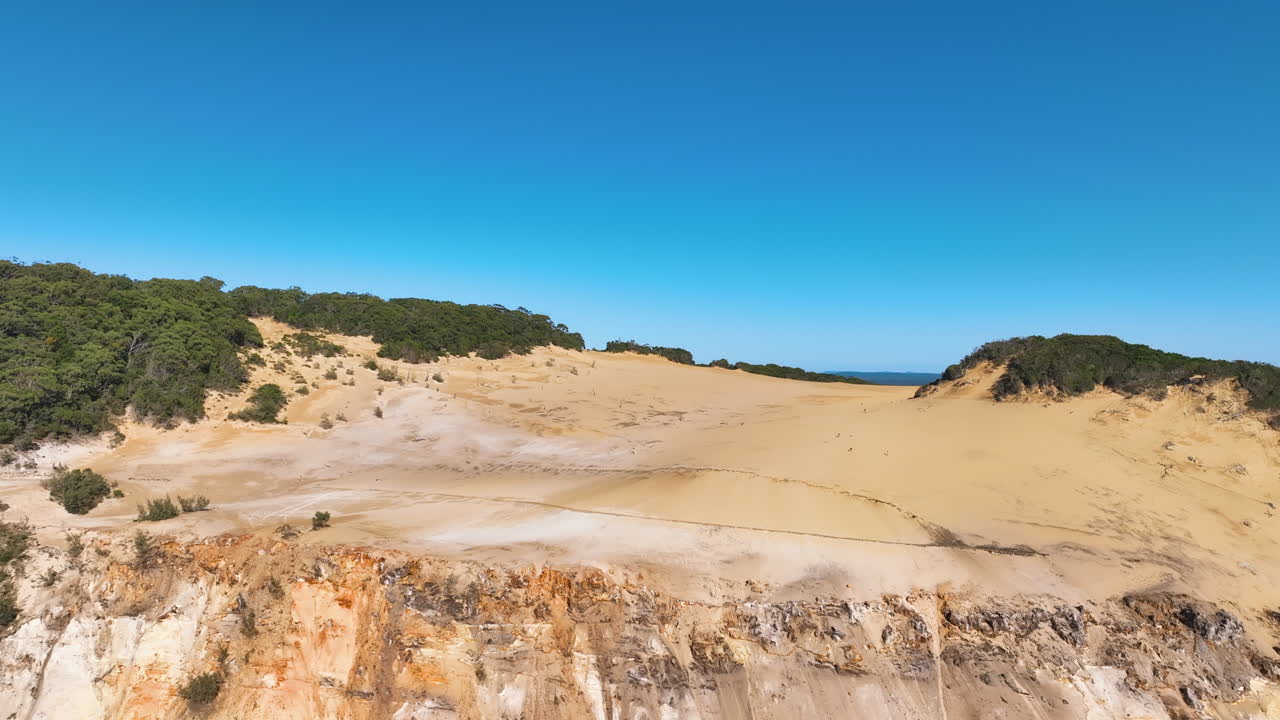 Aerial departs people exploring Rainbow Beach's golden sandy Carlo Sand Blow
