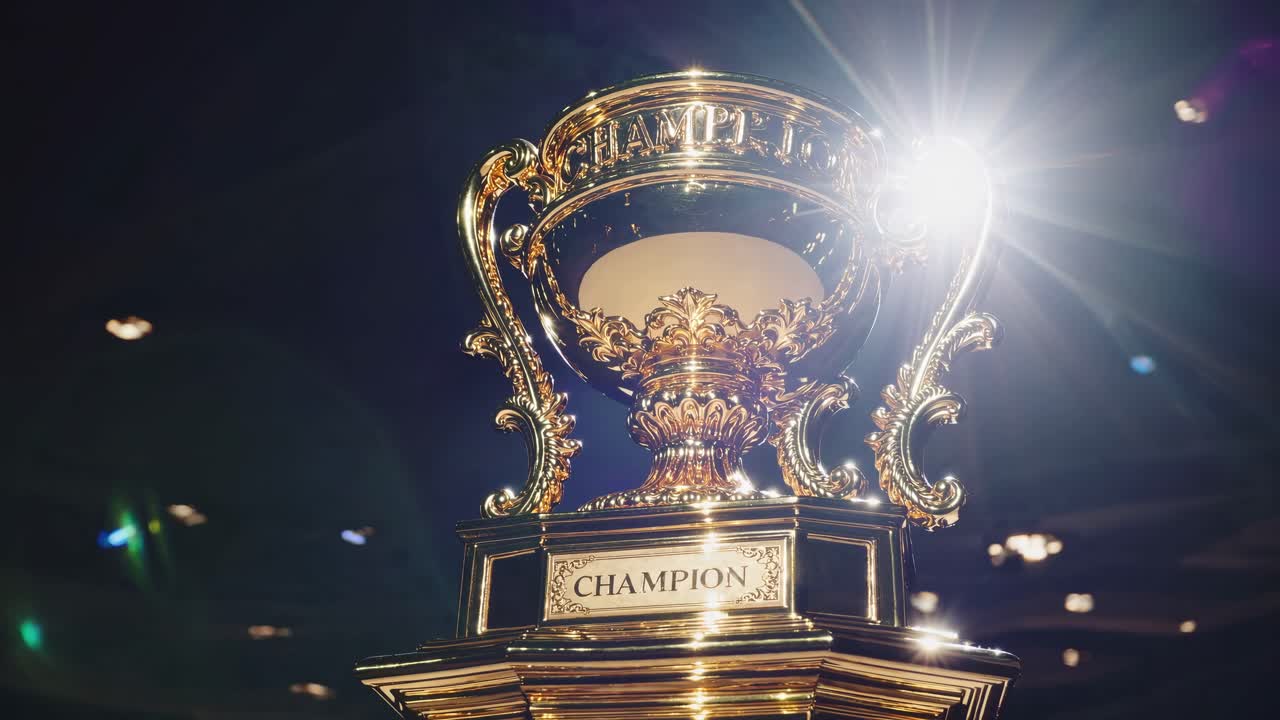 Close-up, low-angle shot of a shining gold trophy labeled 'Champion' with dramatic lighting