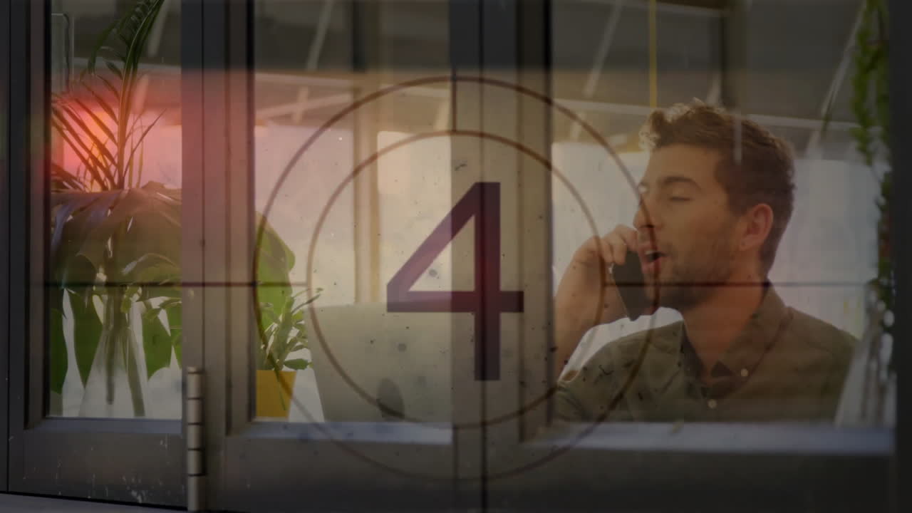 man speaking on smartphone at desk behind glass window, countdown graphic floating in tech scene