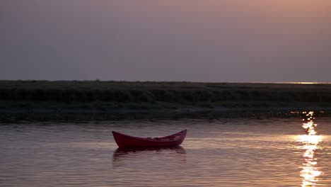 red kayak floating serenely on calm water during sunset, reflecting vibrant colors and distant shores, creating a tranquil and peaceful atmosphere perfect for relaxation