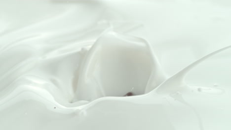 chocolate pieces falling into creamy milk making swirly splashes in macro and slow motion