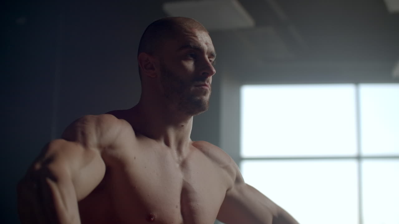 fuerte y decidido culturista masculino atleta deportivo levantando pesas sosteniendo en las manos para entrenar los hombros y la espalda. realice ejercicios para entrenar su espalda en el fondo de la ventana.