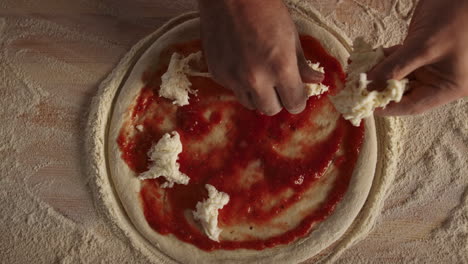 chef cooking homemade pizza in kitchen. pastry cook putting cheese on dough.