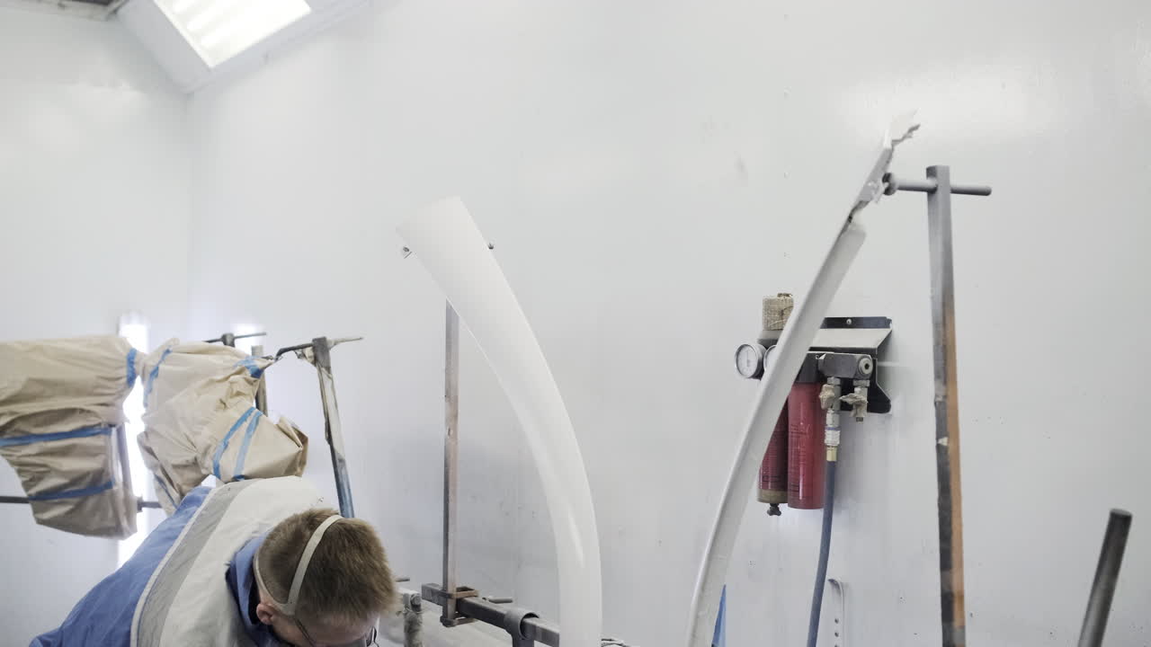 parte del coche siendo pintada con spray en una cabina de pintura