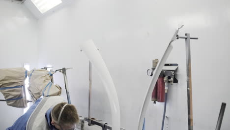 car part being spray painted in a paint booth
