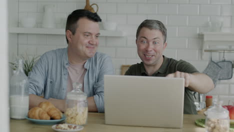 two men in kitchen looking at laptop