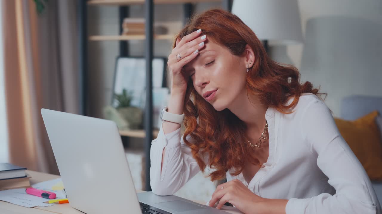 una mujer caucásica frustrada está molesta por las noticias que ve en la computadora portátil.