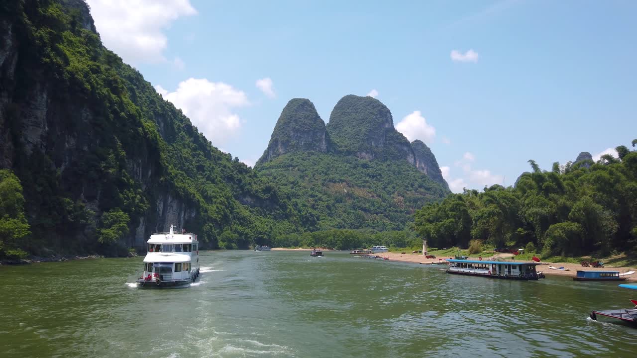 Thuyền du lịch chở khách di chuyển giữa cảnh quan núi đá vôi trên sông Li hùng vĩ từ Quế Lâm đến Dương Sóc.