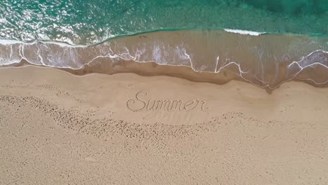 summer written in the sand on a beach