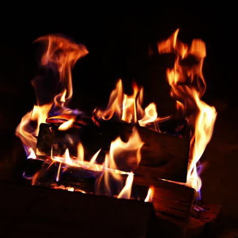 Firewood burning slowly with sparks. Wooden logs in flame inside the fireplace. Detailed hot fire in the brickwork fireplace. Cozy atmosphere