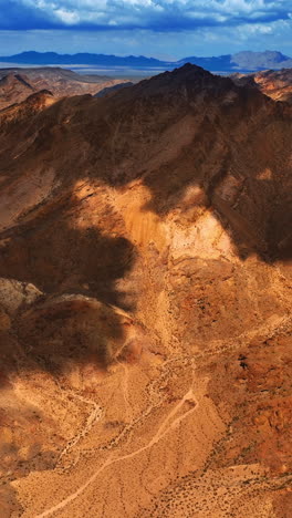 amazing view of red rocks with no vegetation on. clouds shading the rocks in mojave desert, california. aerial view. vertical video