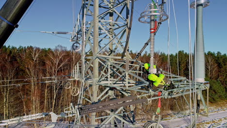 aerial drone zoomed out shot of electrical technicians installing electric pole after climbing up high on a sunny day