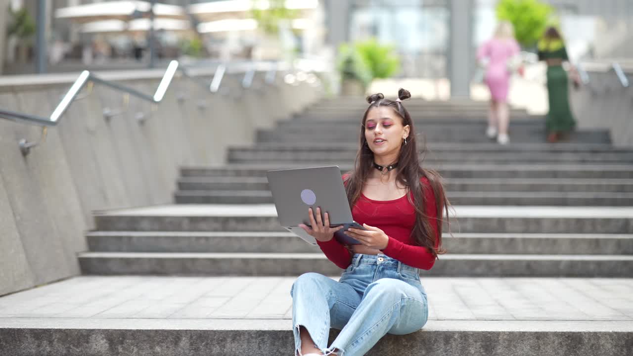 mujer joven trabajando en una computadora portátil en las escaleras de la ciudad