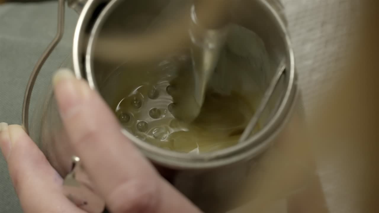 Primo piano di un artista professionista che mescola solvente per vernici in un contenitore di metallo.