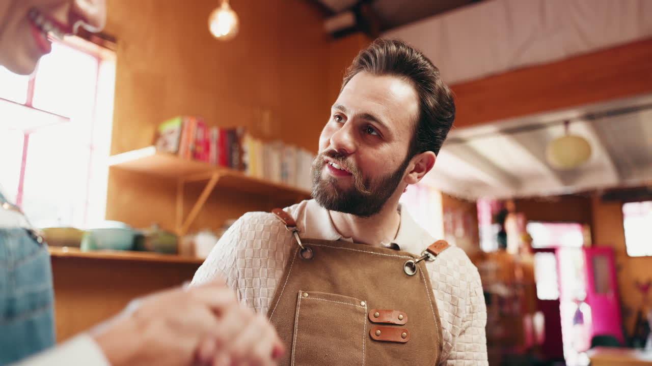 Un uomo con un grembiule sorride e batte il cinque a un cliente