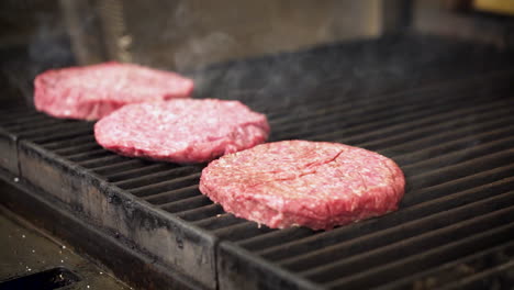 cook seasons sizzling hamburger patties as smoke rises from grill, 4k