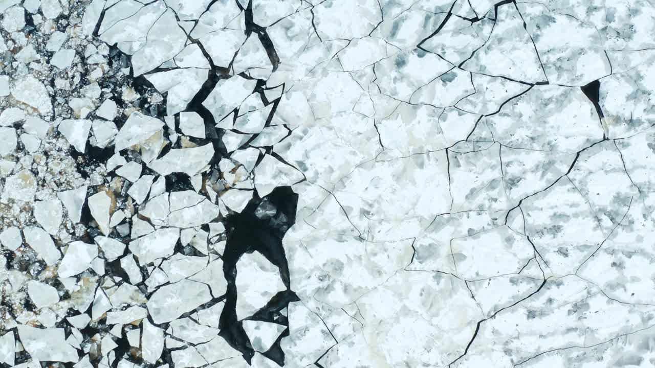 Aerial fly over view of cracked ice floes floating in the sea
