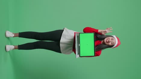 mujer sosteniendo una computadora portátil con pantalla verde con un sombrero de santa