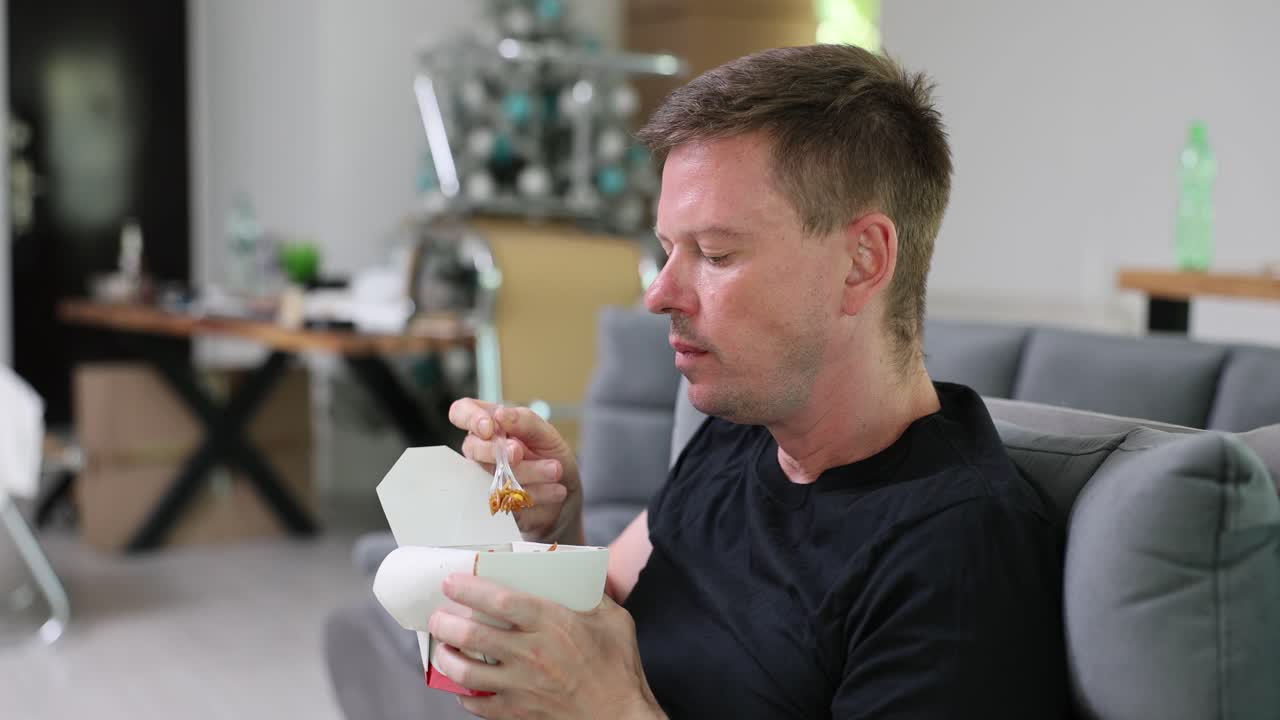 Man Eating Takeout Food on Sofa at Home