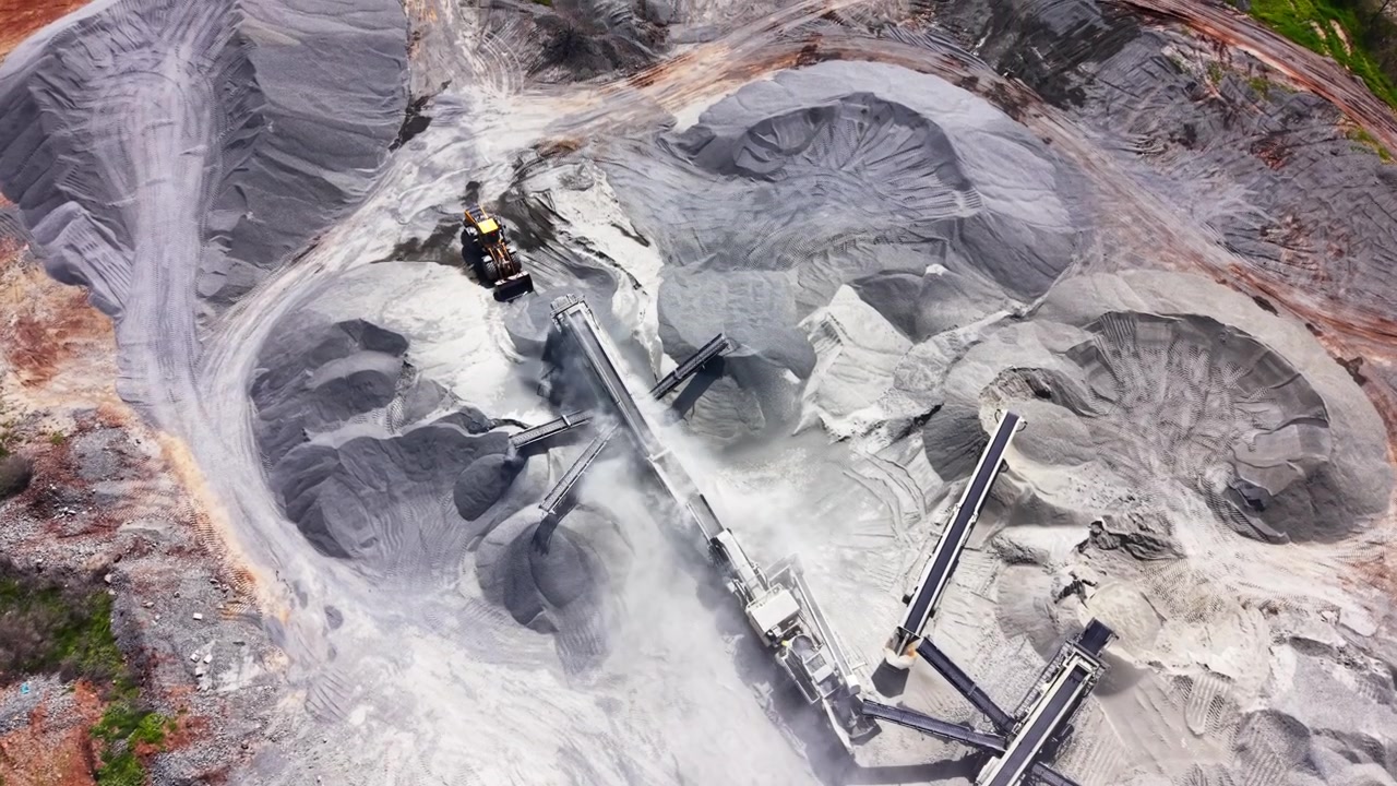 Overhead drone shot of industrial conveyor belts sorting gravel into massive stone piles at an aggregate mine. Aerial view of quarry crushing machine, Bulgaria