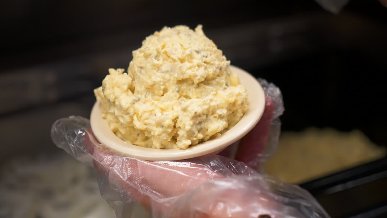 saca ensalada de patata y la coloca en un tazón, cámara lenta 4k