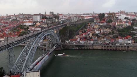 rabelo boat navigates under dom luis i bridge while people cross over it