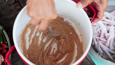 chef´s hand using spoon preparing sauce for chicken feet asian dish - close up