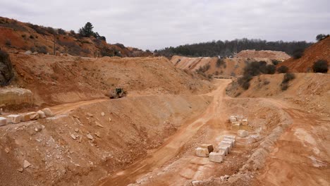 Loader-excavator-carrying-stone-load-in-limestone-quarry,-Pan-left-shot