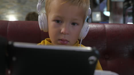 child in headphones watching cartoon on mobile