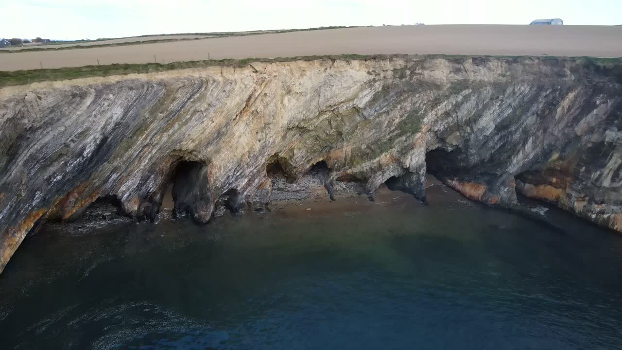 imágenes aéreas de acantilados escarpados con cuevas y costas naturales salvajes en una tarde tranquila en irlanda