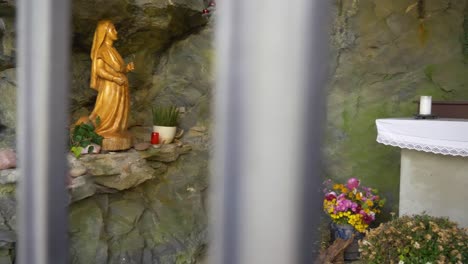 panning shot behind a fence to an altar in a grotto