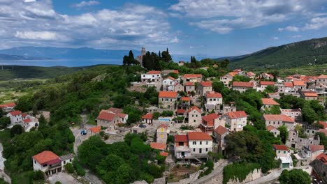 aerial: top of the hill of hvar during the day with fortress and adriatic sea in the back in croatia, orbit drone shot