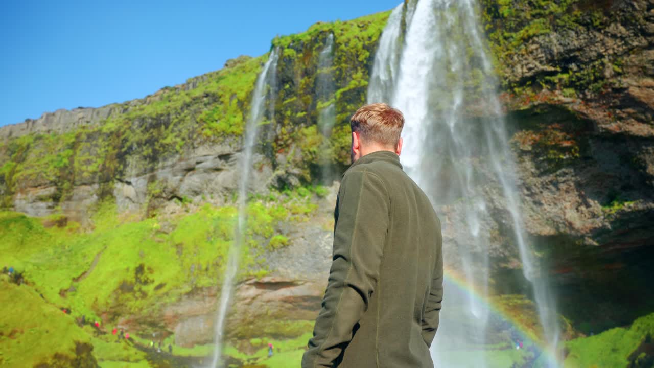 hombre caucásico frente a las impresionantes cascadas de seljalandsfoss en el sur de islandia
