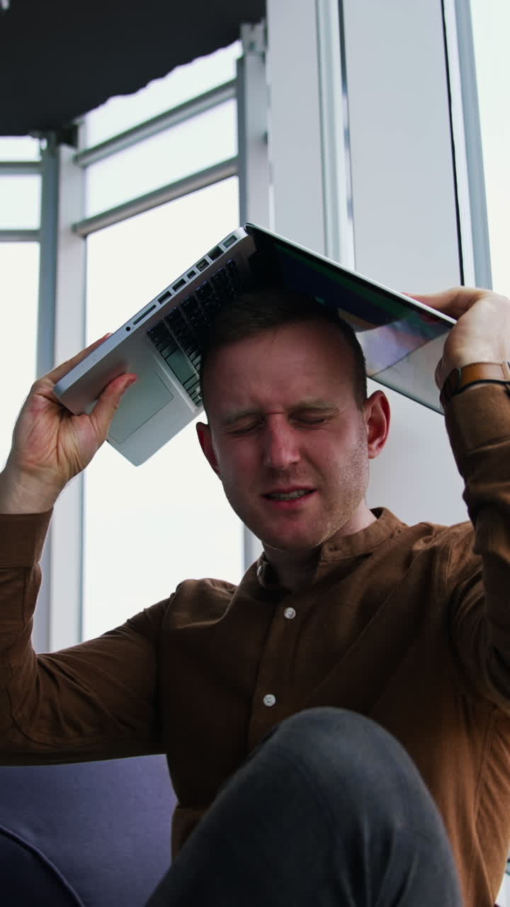 young man sitting on a floor with laptop computer. Work stress concept of man Vertical video