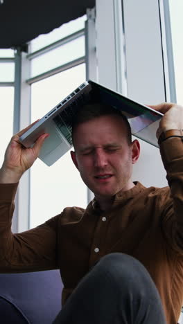 young man sitting on a floor with laptop computer. work stress concept of man vertical video