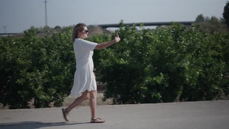 woman walking in an orchard, taking pictures with a mobile phone